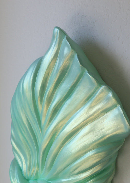 Turquoise ceramic leaf wall art on a plain background